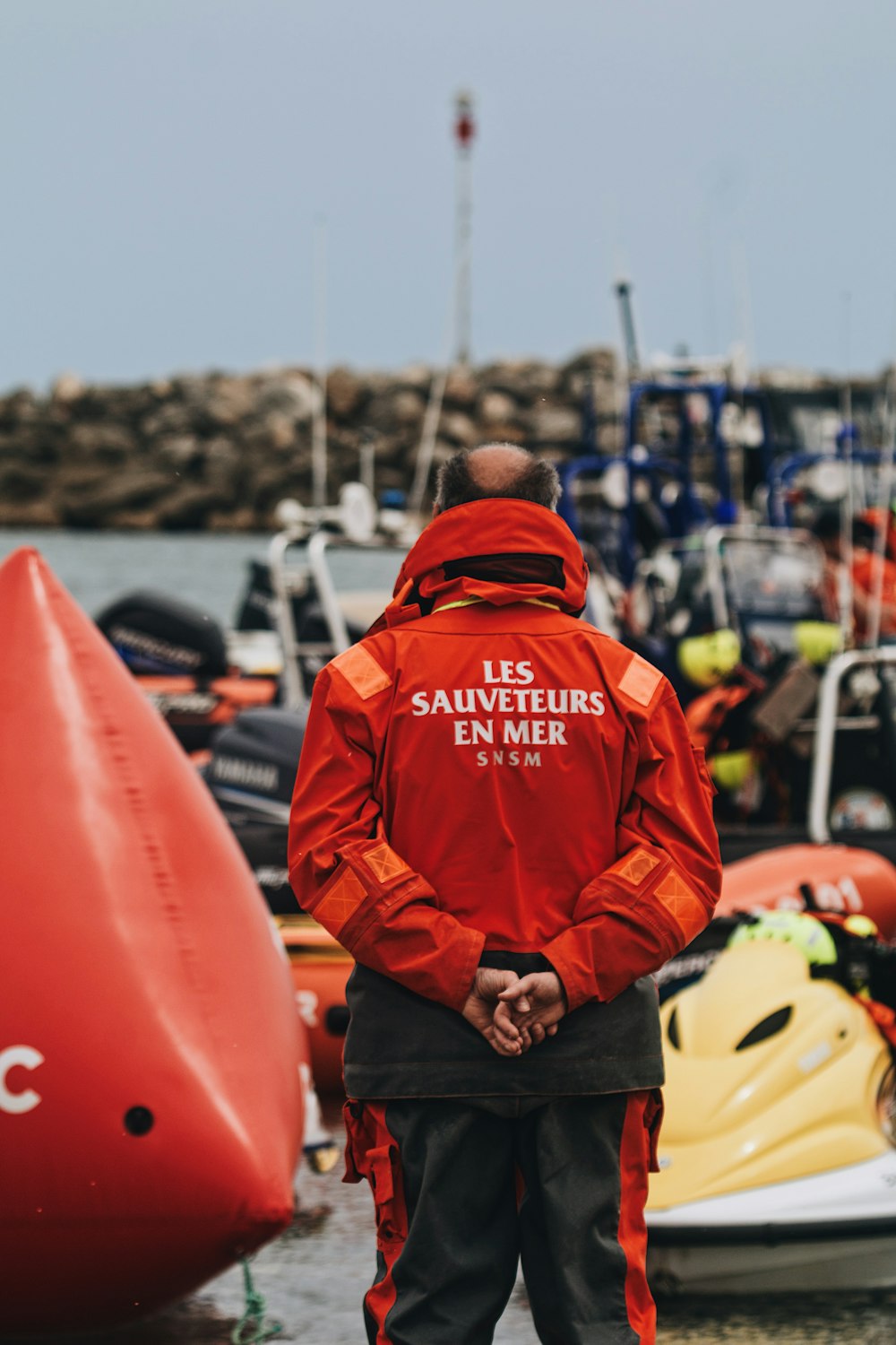 a man in a red jacket standing next to a red boat