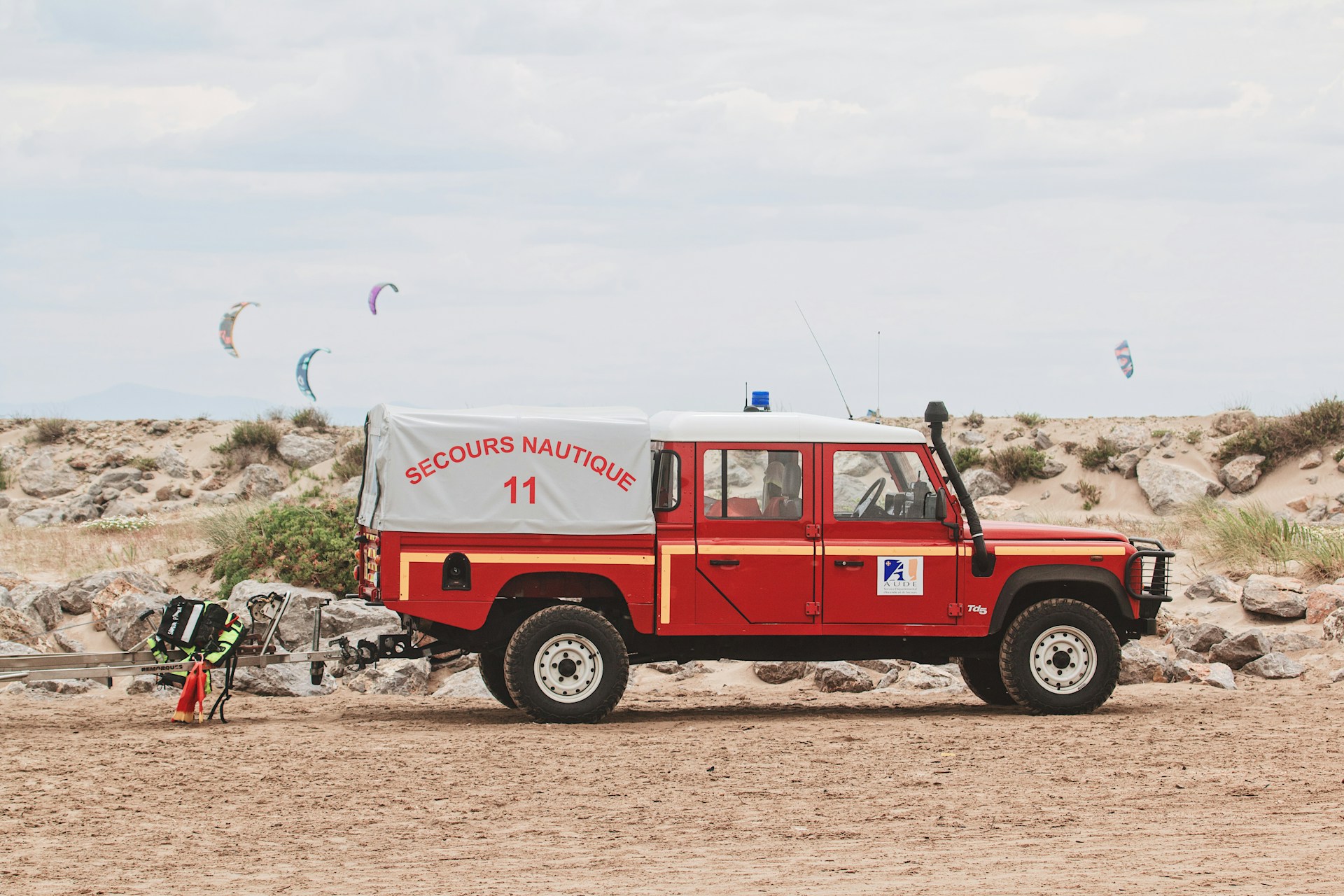 a red and white truck parked on top of a sandy beach