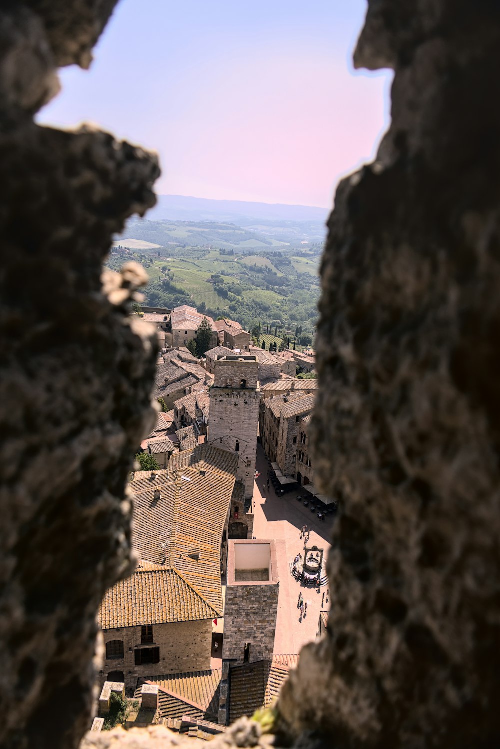 a view of a town through a hole in a rock wall
