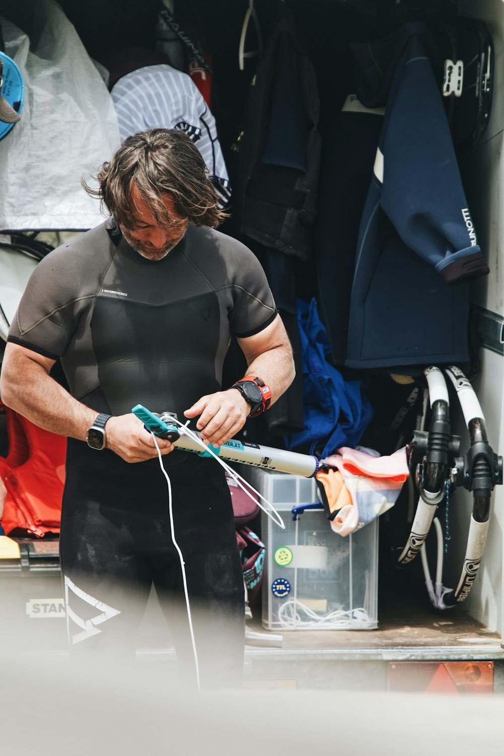 ein mann in einem neoprenanzug, der ein surfbrett hält