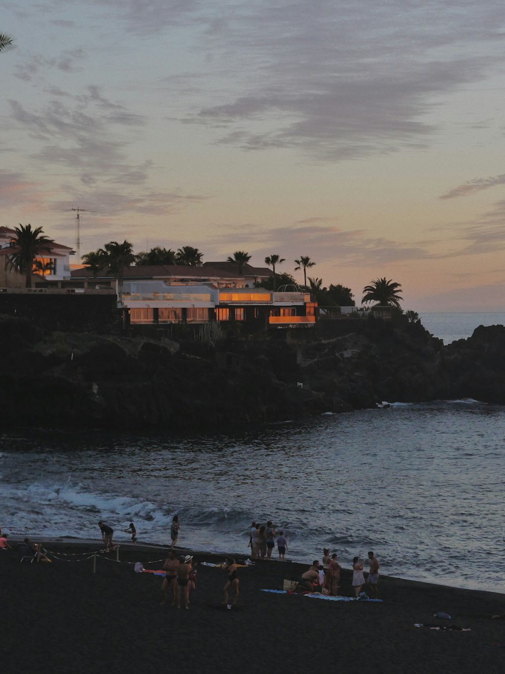 a group of people standing on top of a beach next to the ocean