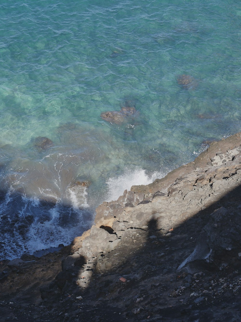 a man sitting on a rock next to the ocean