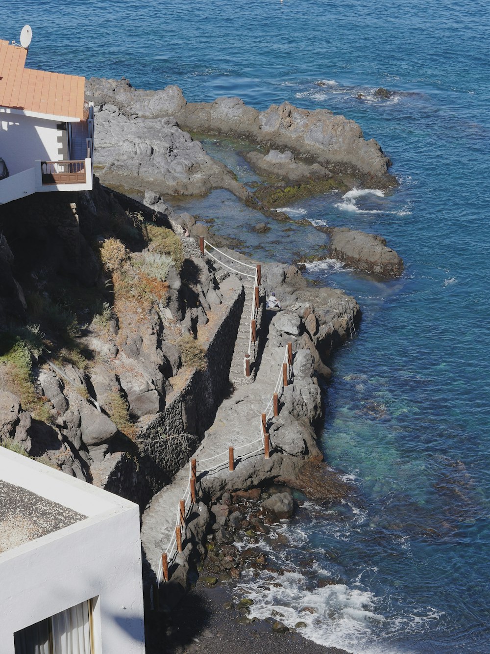 a house sitting on top of a cliff next to the ocean