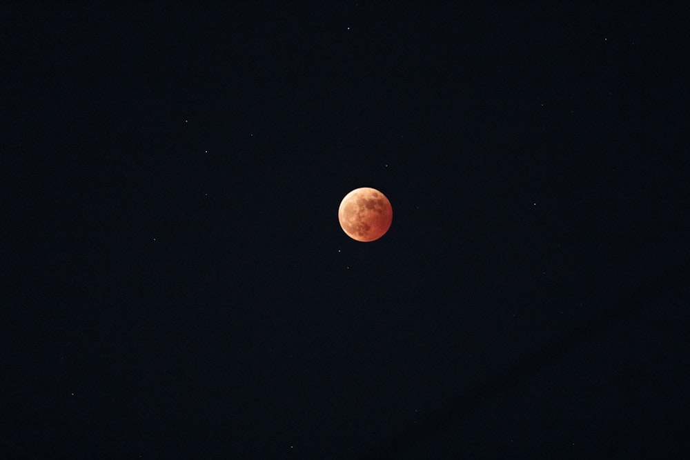 a red moon is seen in the dark sky