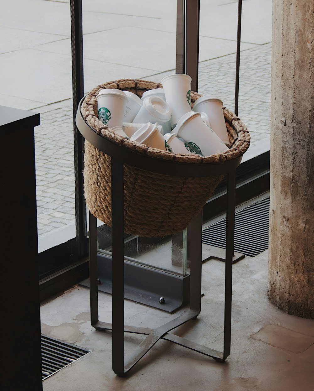 a basket filled with cups sitting on top of a metal stand