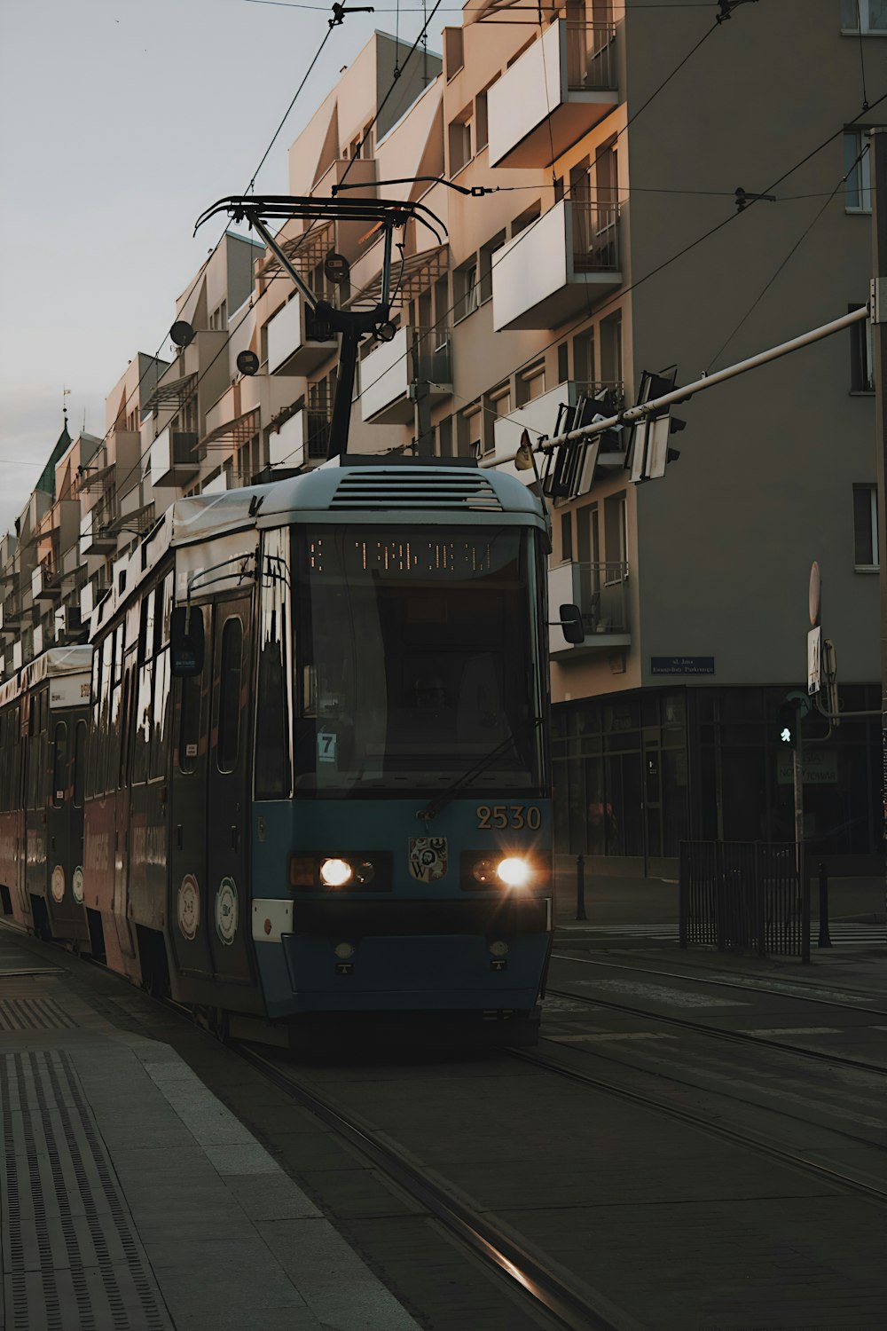 a train traveling down a street next to tall buildings