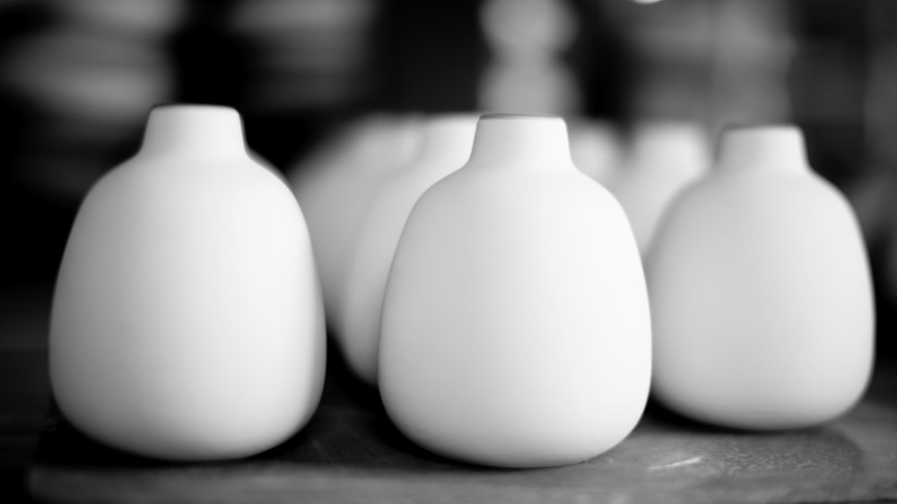 eine Gruppe weißer Vasen, die auf einem Tisch sitzen