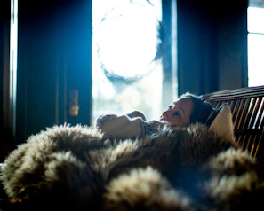 A cozy rest blanket draped casually over a wooden bench near a window.