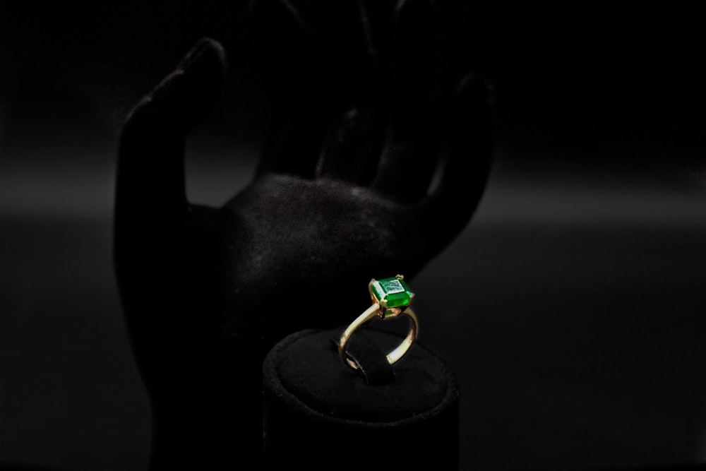 a green ring sitting on top of a black stand