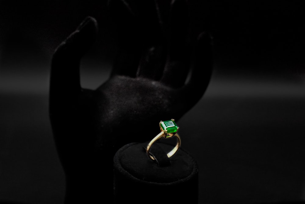 Un anillo verde sentado encima de un soporte negro