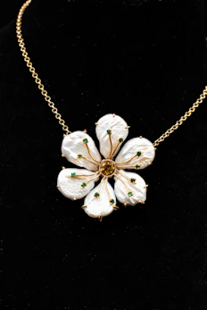 a necklace with white flowers on a gold chain