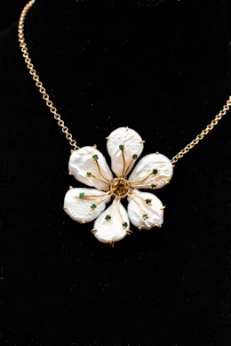 a necklace with white flowers on a gold chain