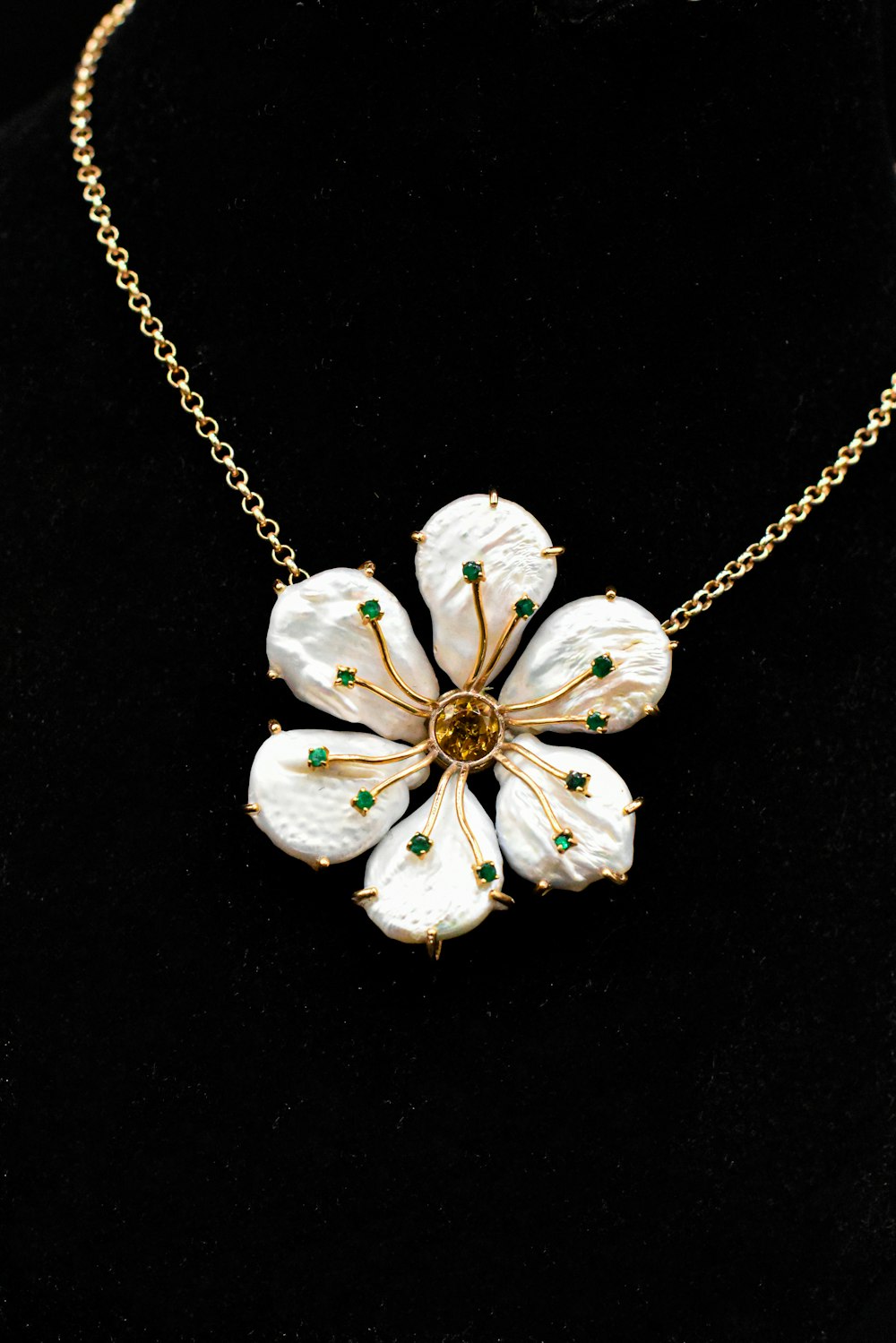 un collar con flores blancas en una cadena de oro