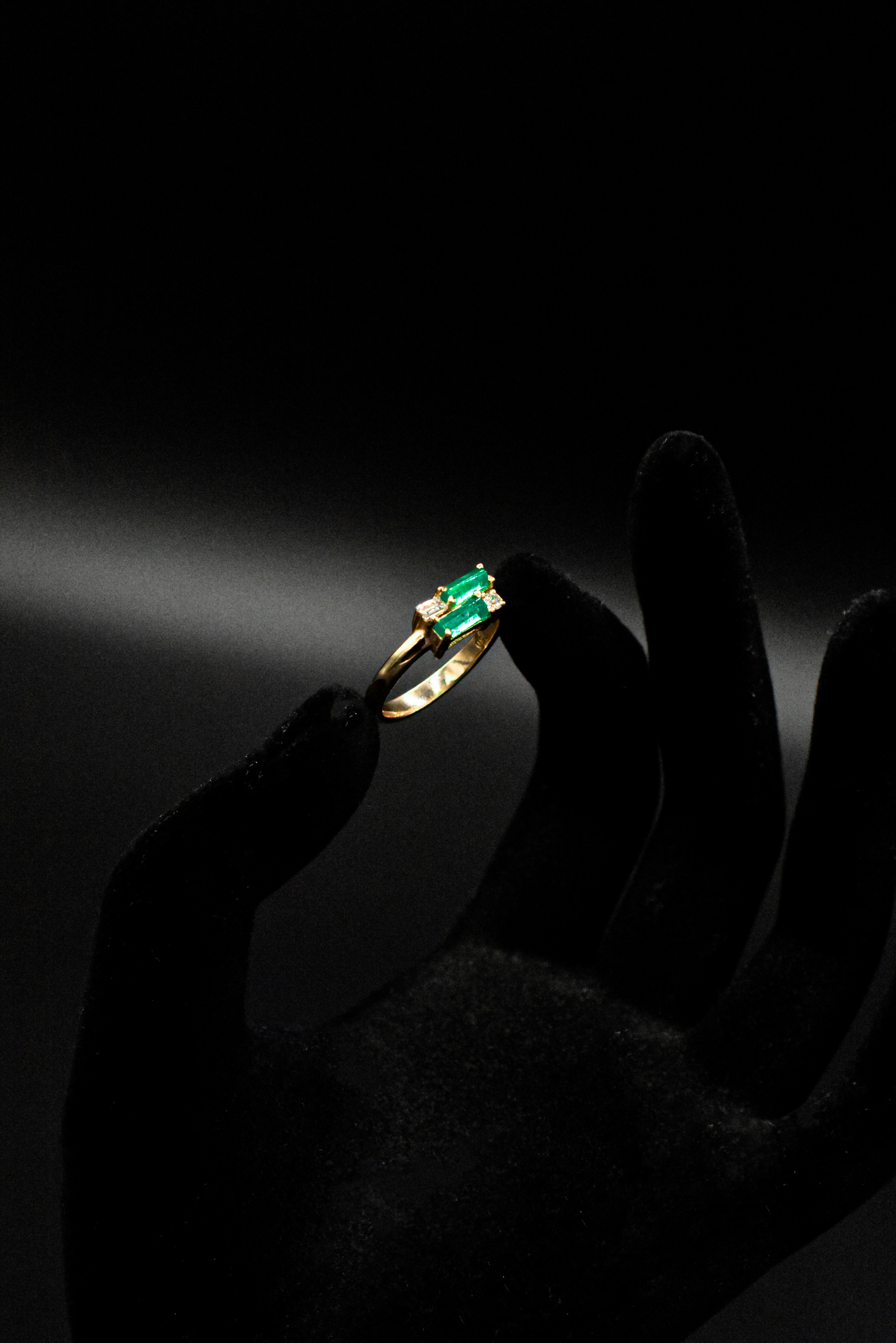 a person's hand holding a ring with a green stone