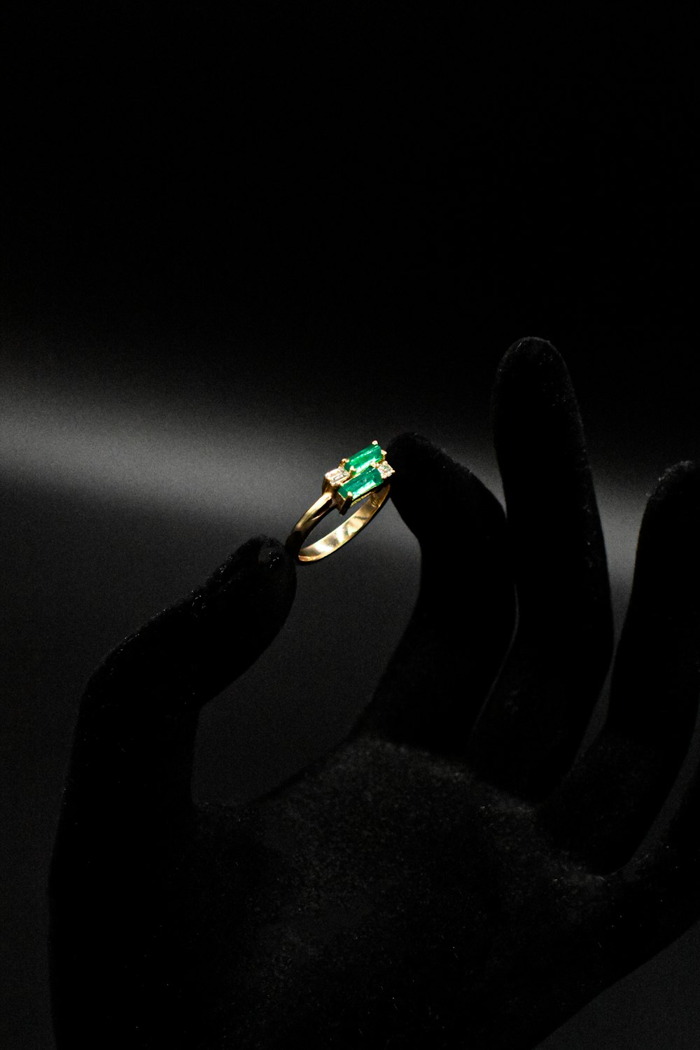 Die Hand einer Person, die einen Ring mit einem grünen Stein hält