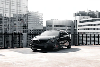 A sleek black car parked in a modern urban setting at dusk, reflecting the premium and professional tone of imonycars.