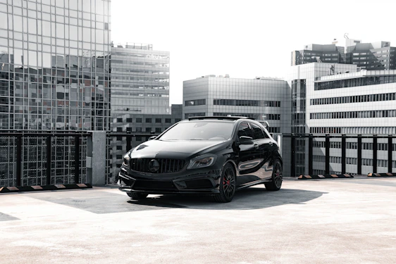 A sleek black car parked in a modern urban setting at dusk, reflecting the premium and professional tone of imonycars.