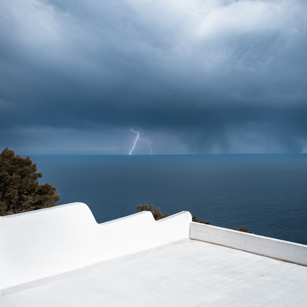 a lightning bolt is seen in the distance over the ocean