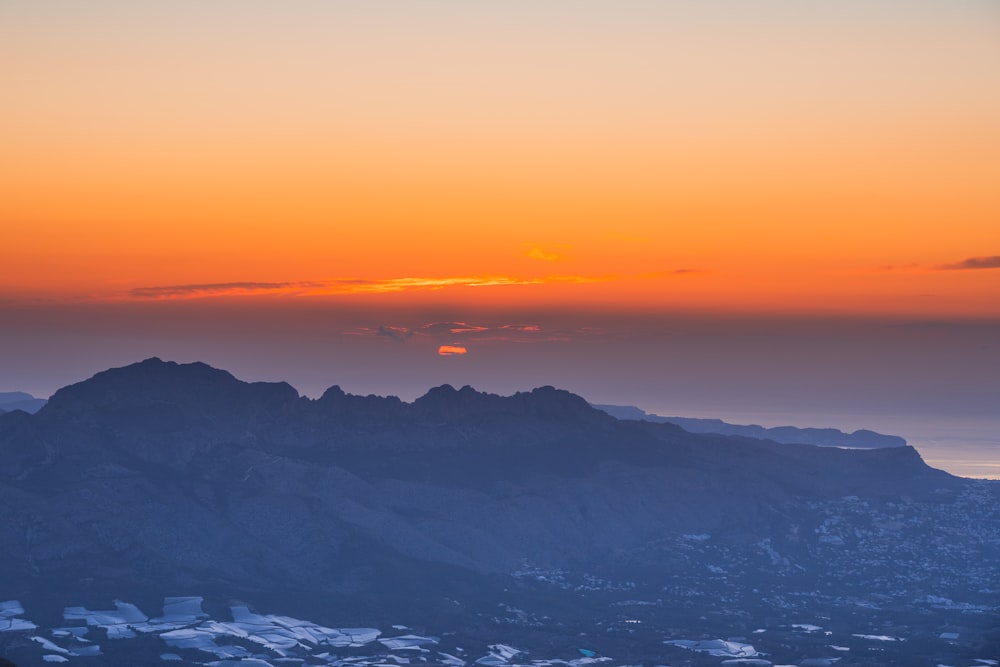 the sun is setting over a mountain range