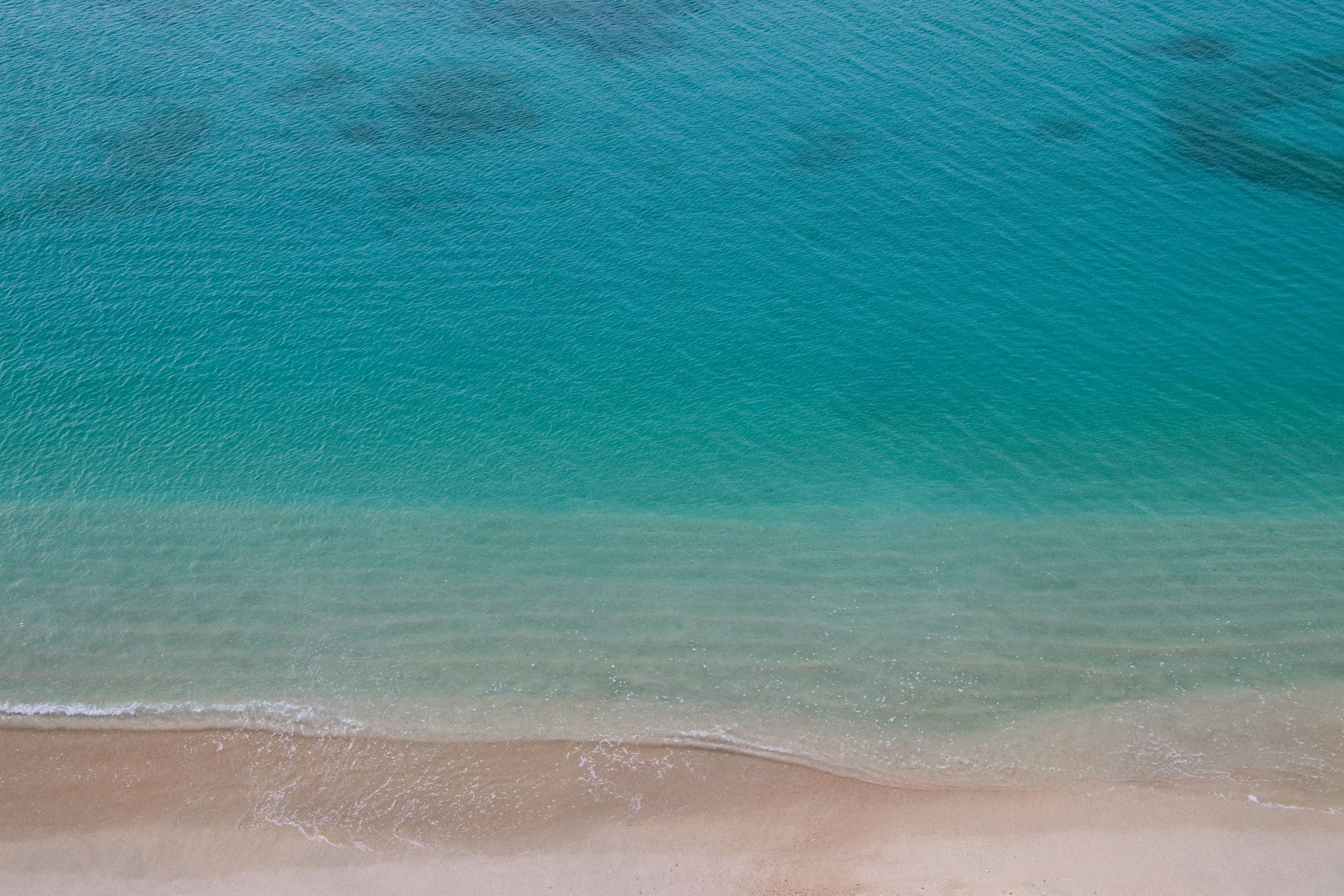 an aerial view of a beach with a boat in the water