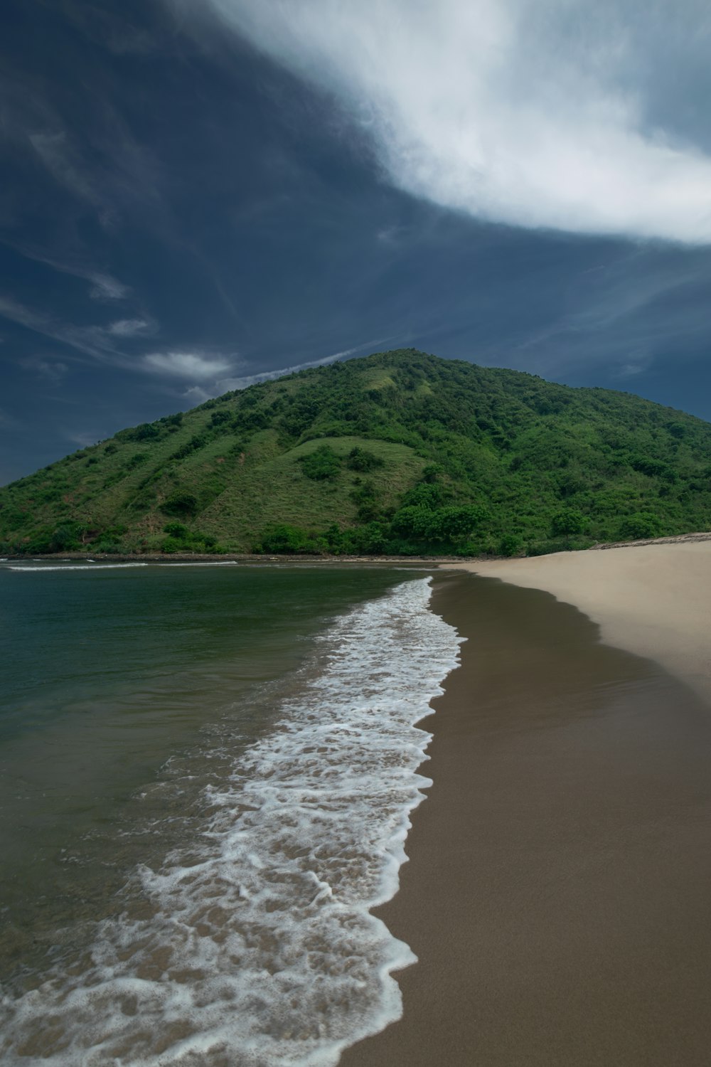 a sandy beach with a hill in the background