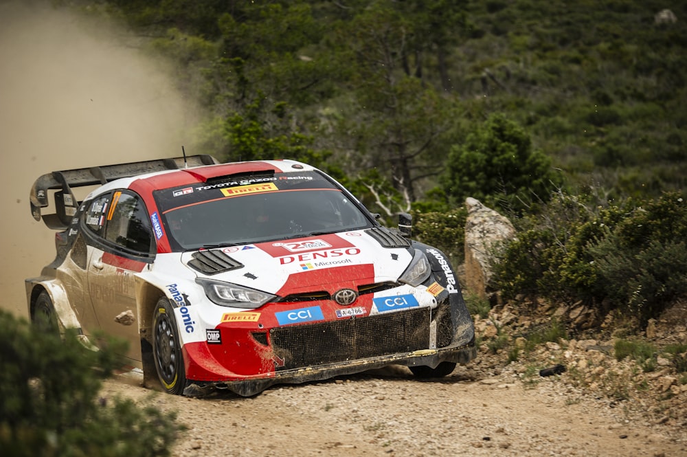 a red and white car driving down a dirt road