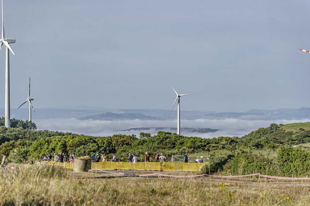 a group of people standing next to wind turbines