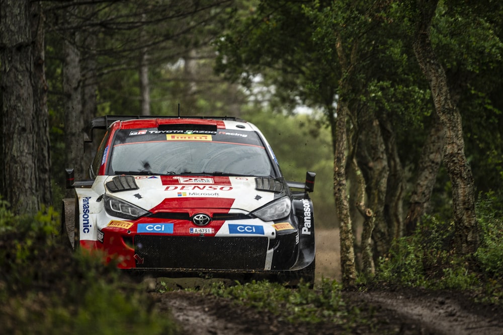 a red and white car driving down a dirt road