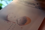 A magazine cover featuring a cracked eggshell with tally marks inside, symbolizing passage of time or captivity. Small shapes resembling birds are flying out from the egg, suggesting freedom or escape. The title 'Nightingale' and the season 'Spring 2023' are visible at the top.