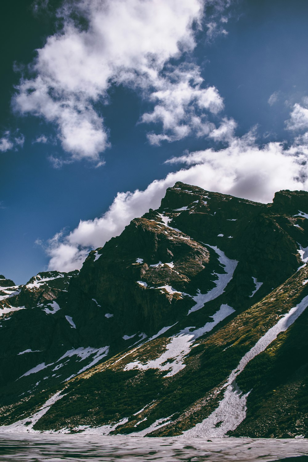 a snow covered mountain under a cloudy blue sky