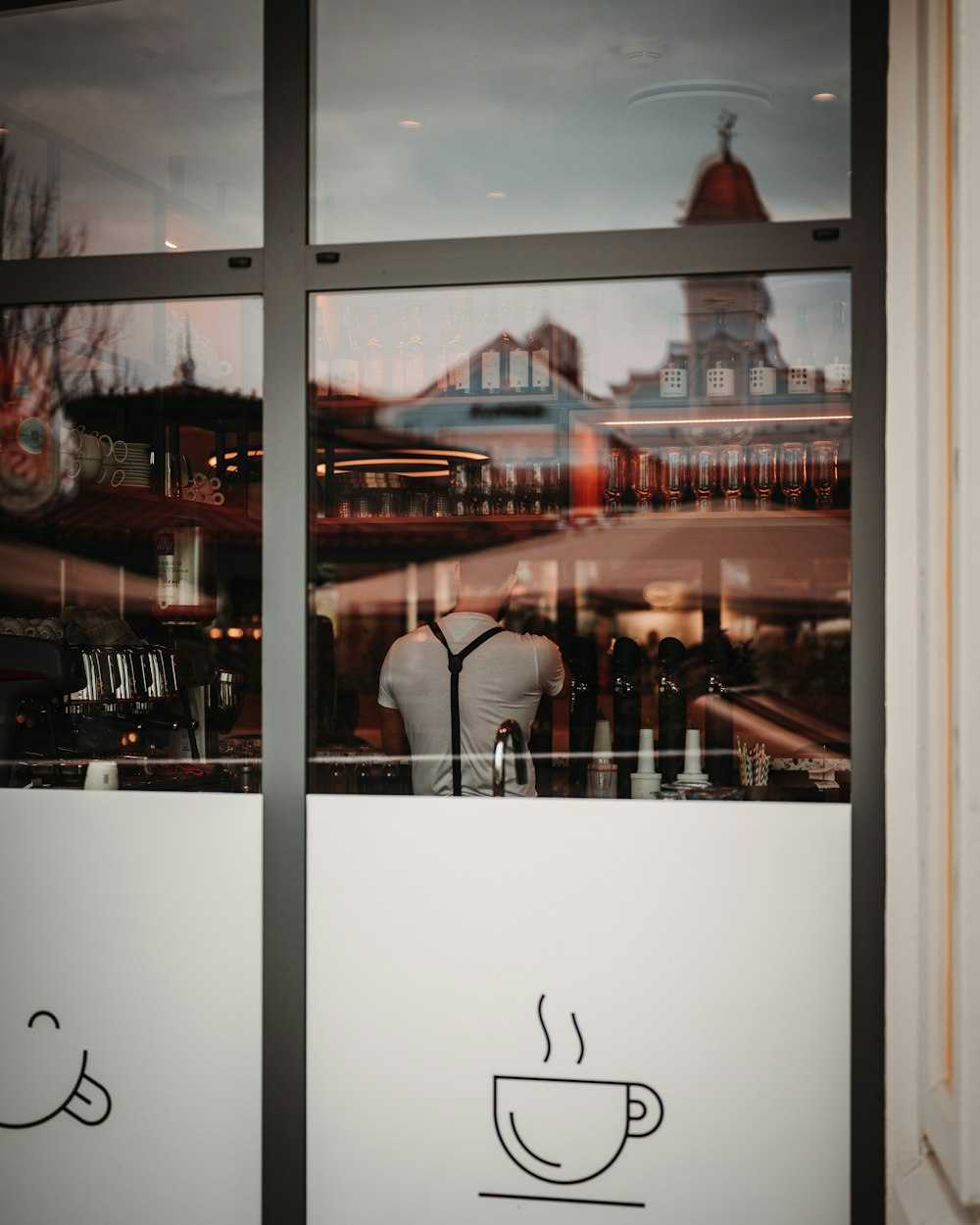 a mannequin in front of a window with a coffee cup drawn on it