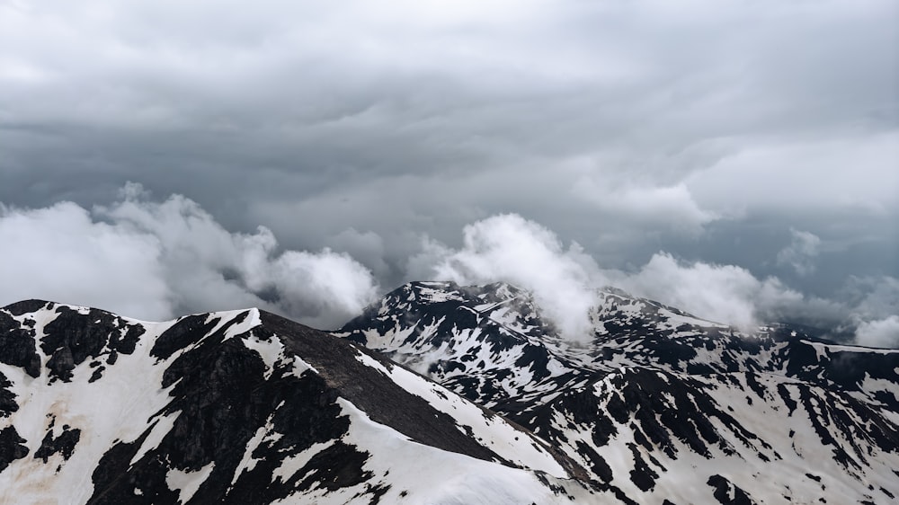 a mountain range covered in snow under a cloudy sky