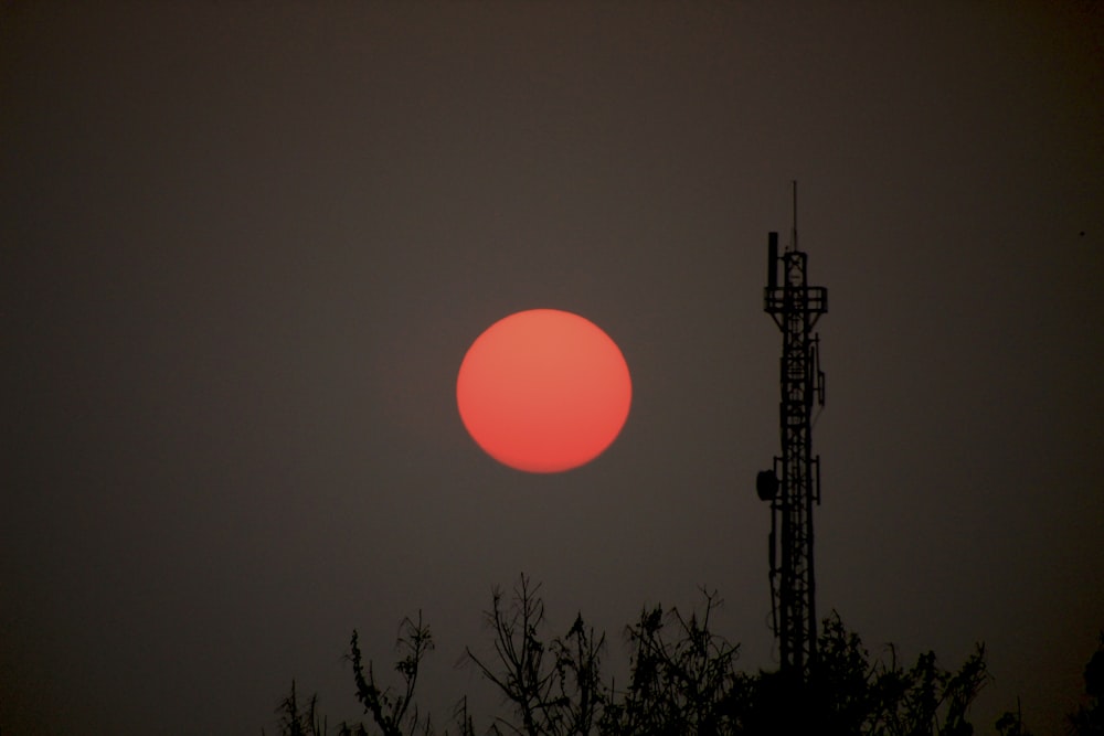 the sun is setting behind a radio tower