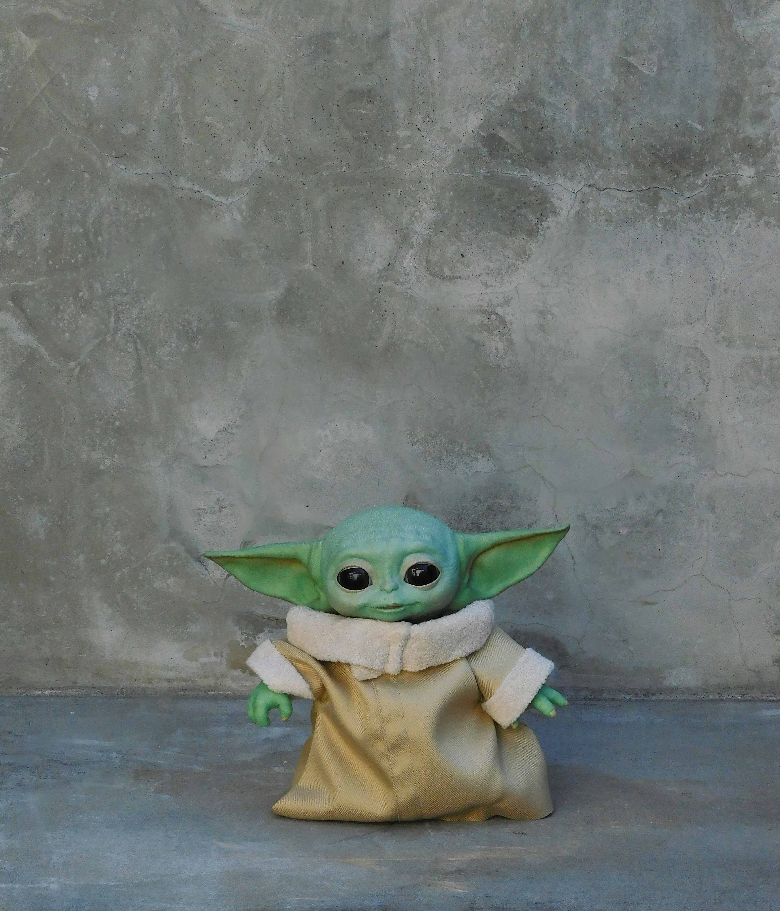 a baby yoda figurine sitting on the ground