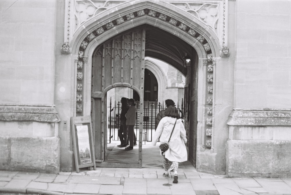 a black and white photo of people entering a building