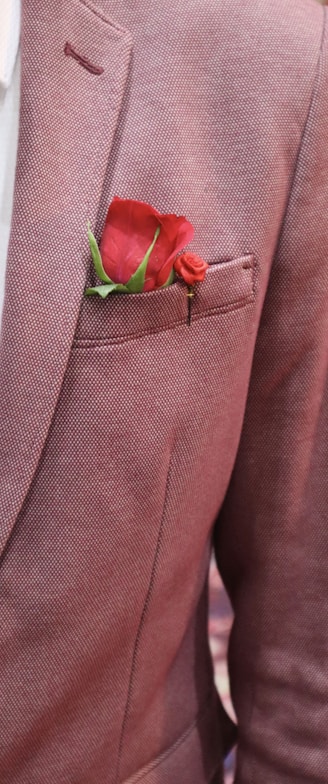 a man in a suit with a red rose in his pocket