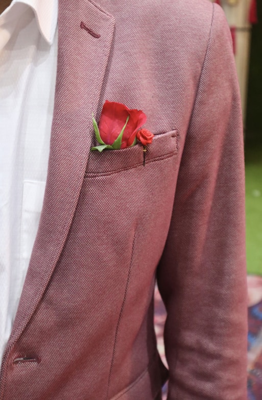 a man in a suit with a red rose in his pocket