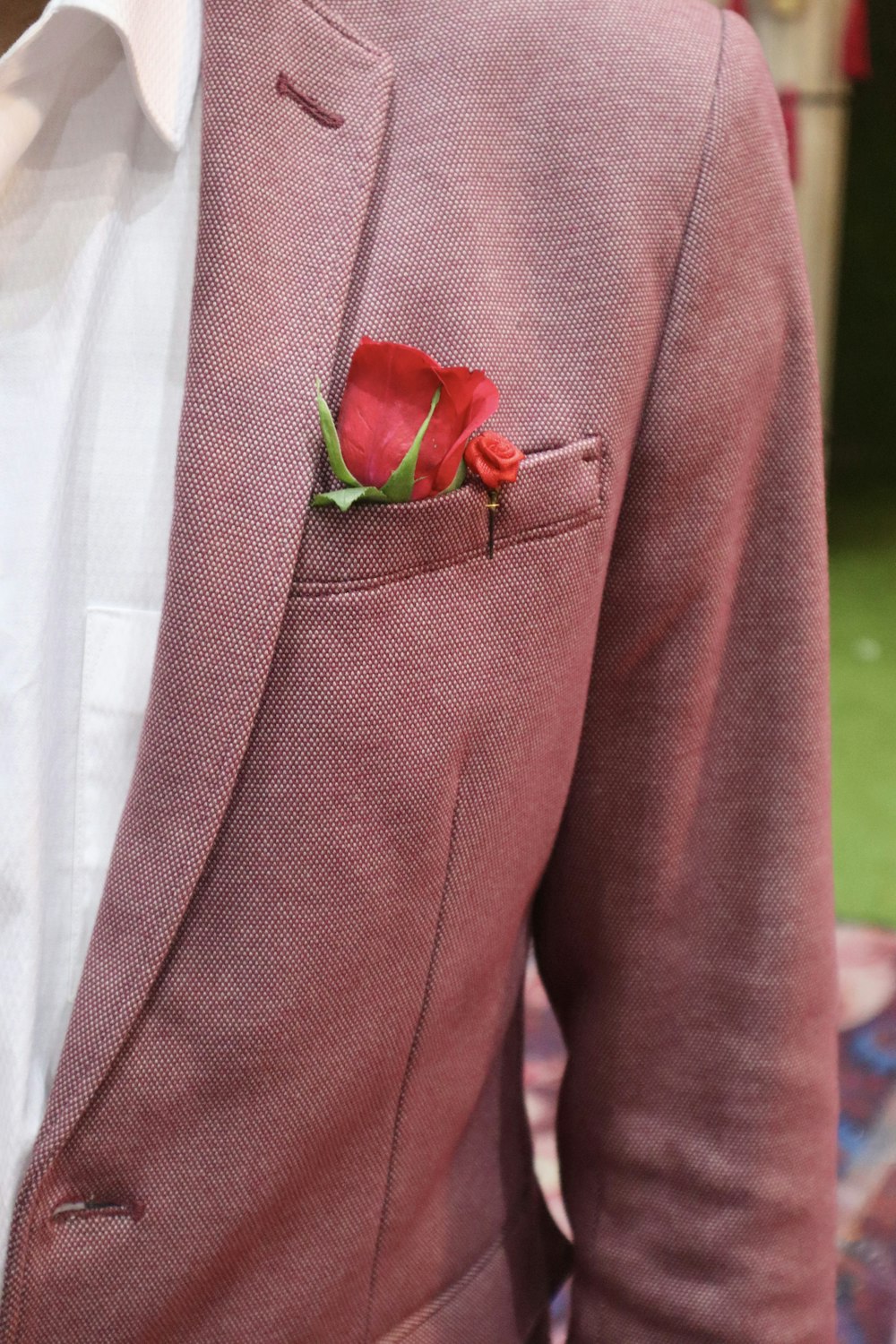 a man in a suit with a red rose in his pocket