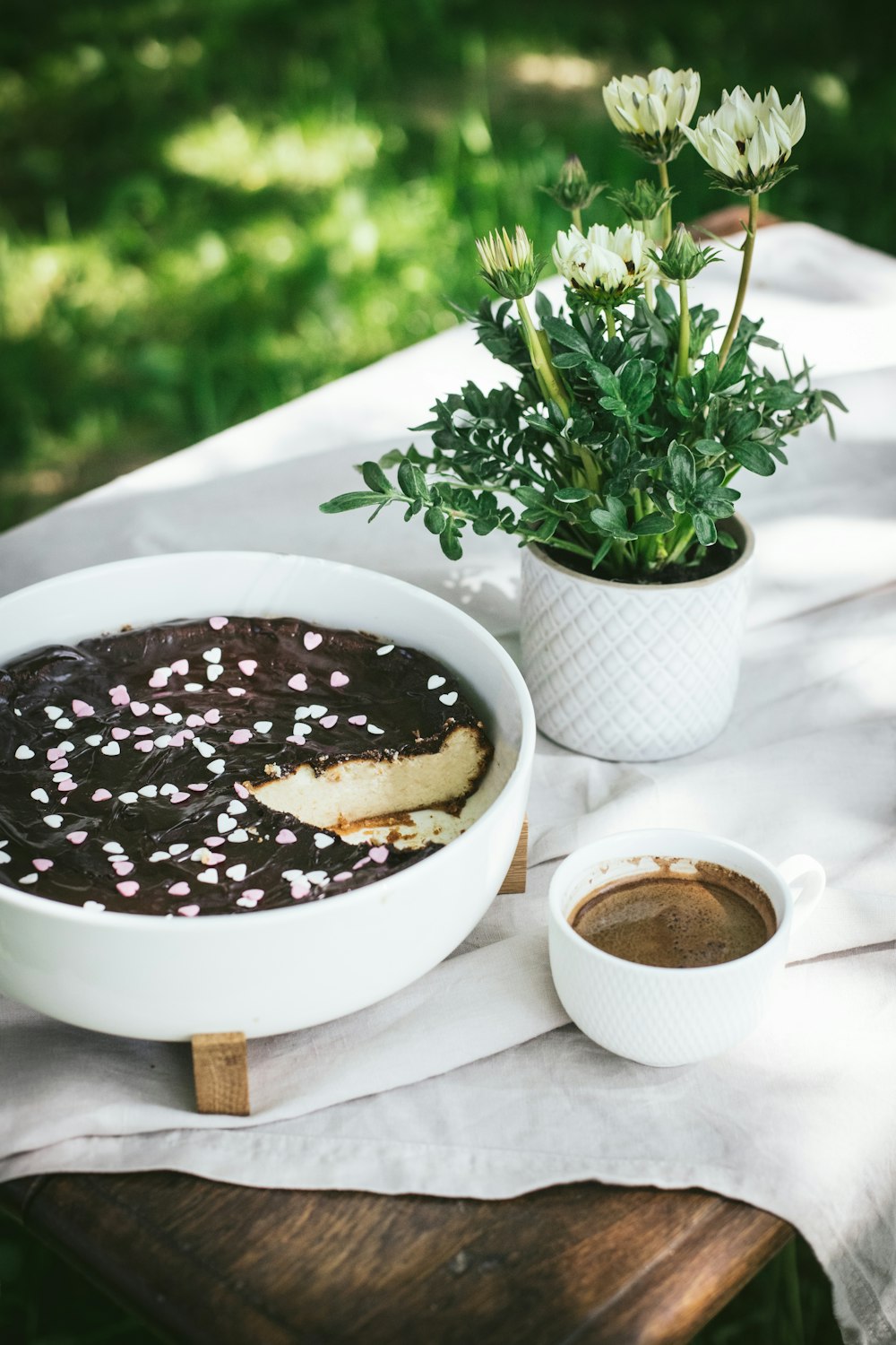 a table topped with a bowl of cake next to a cup of coffee