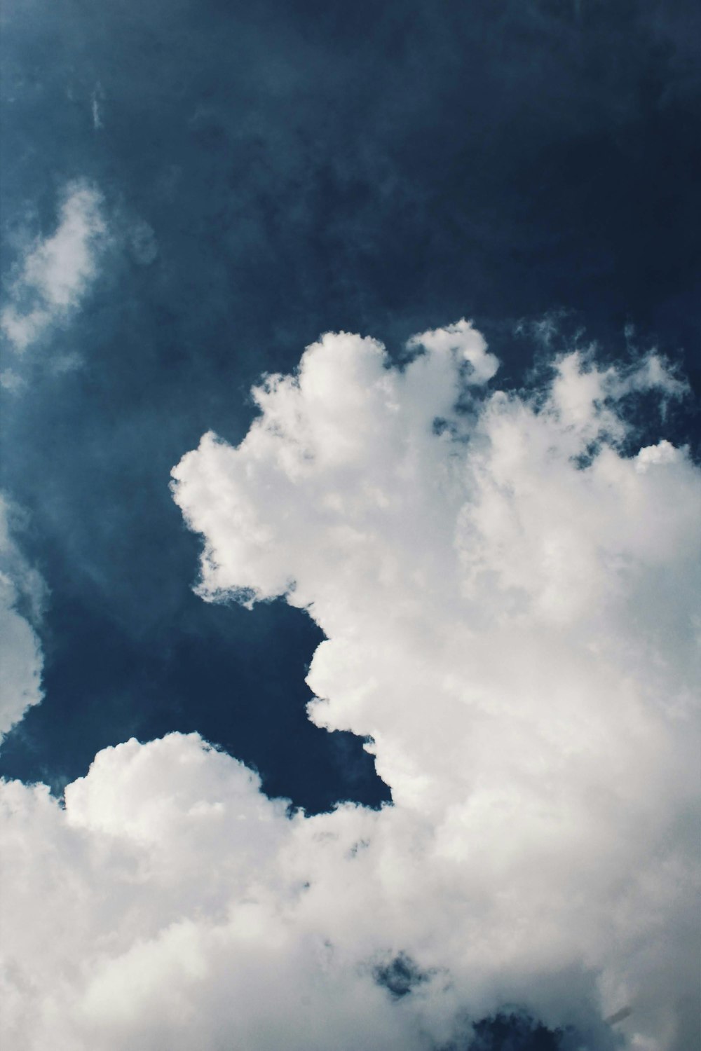 a plane flying through a cloudy blue sky