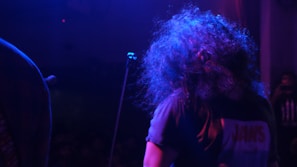 Bigg Britt striking a bold pose on stage with electric blue spotlight highlighting her signature style.