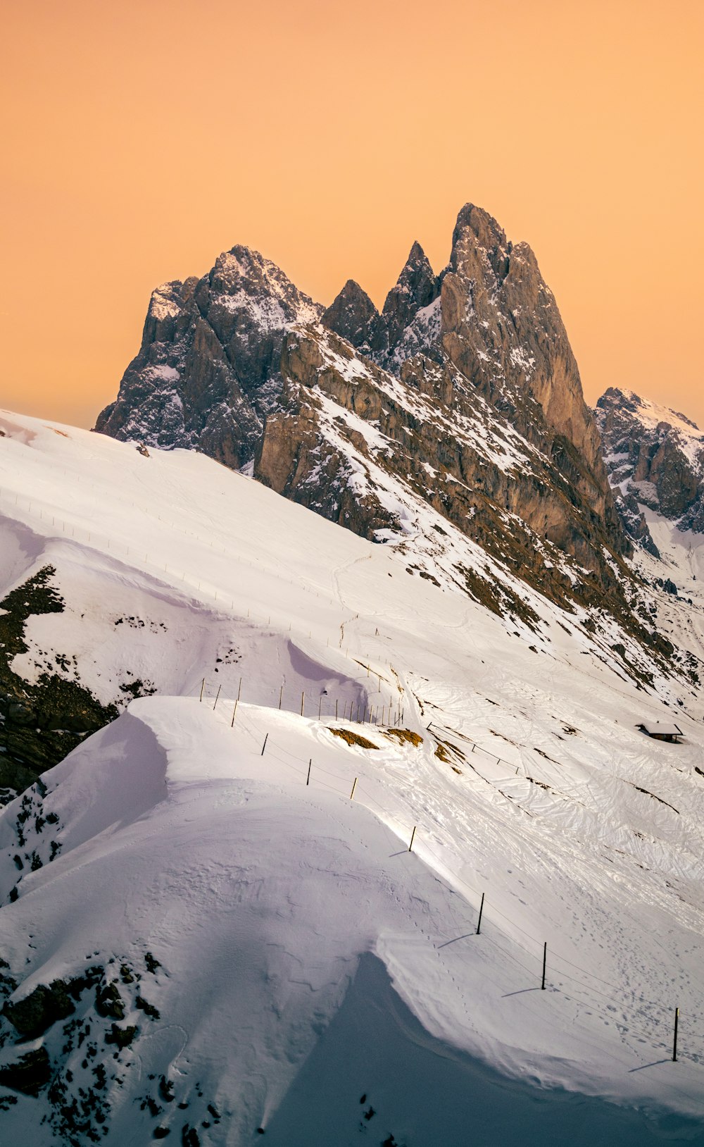 a snow covered mountain with a fence in the foreground