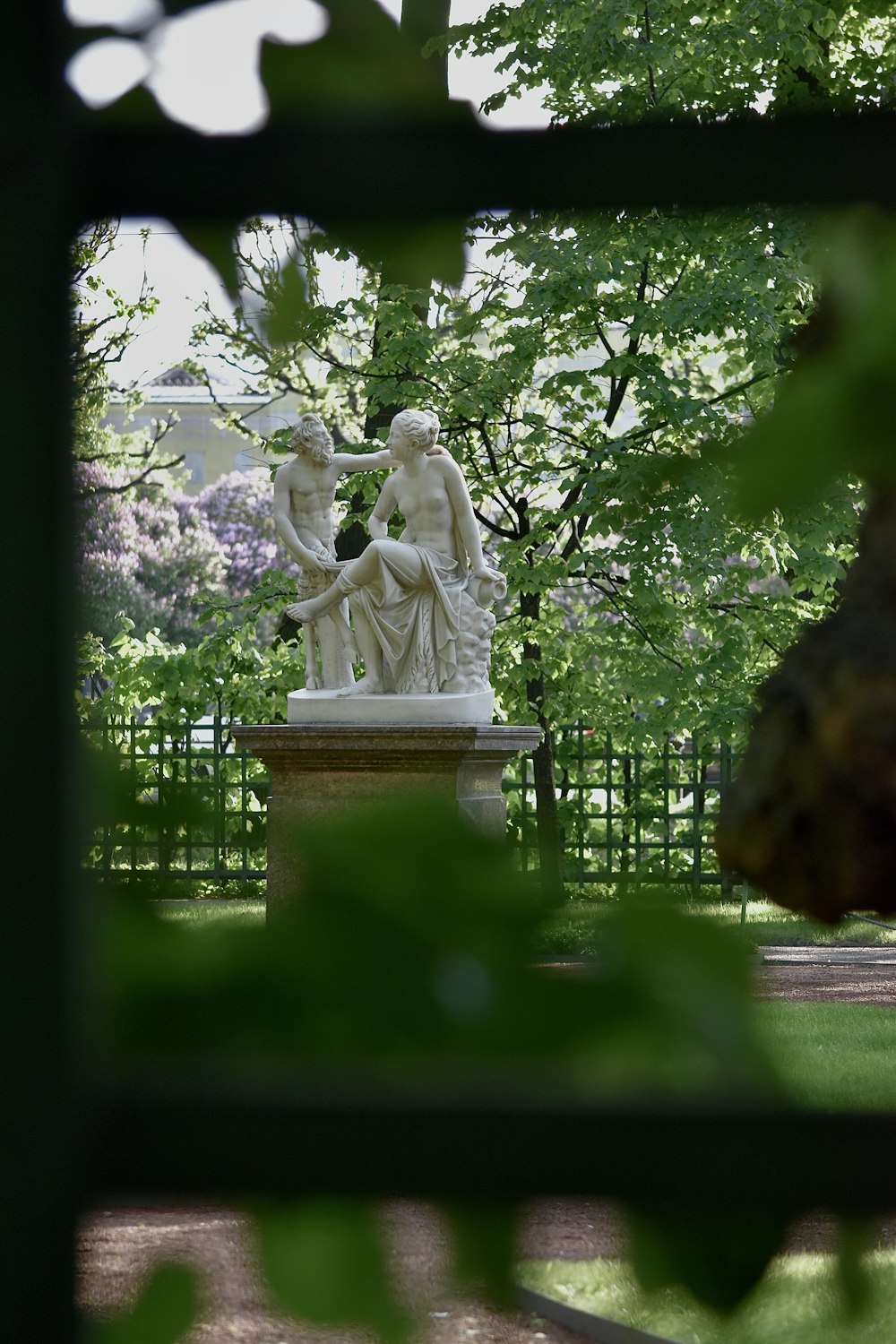 a statue of two people sitting on a bench in a park