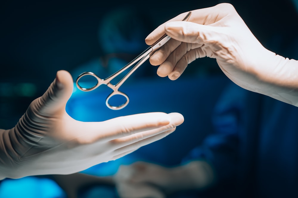 a pair of hands holding a pair of surgical scissors