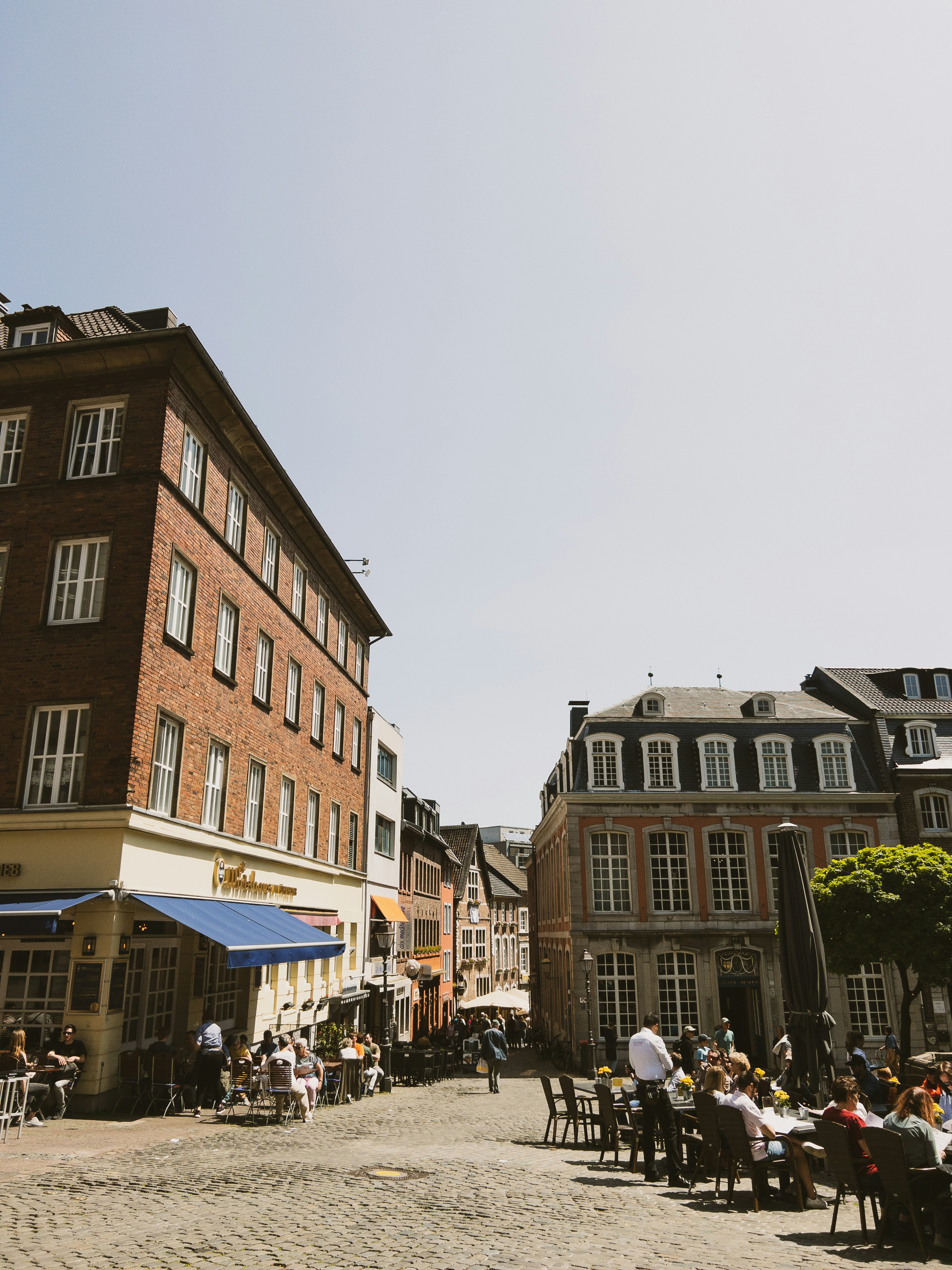 eine gruppe von menschen, die an tischen vor einem gebäude sitzen