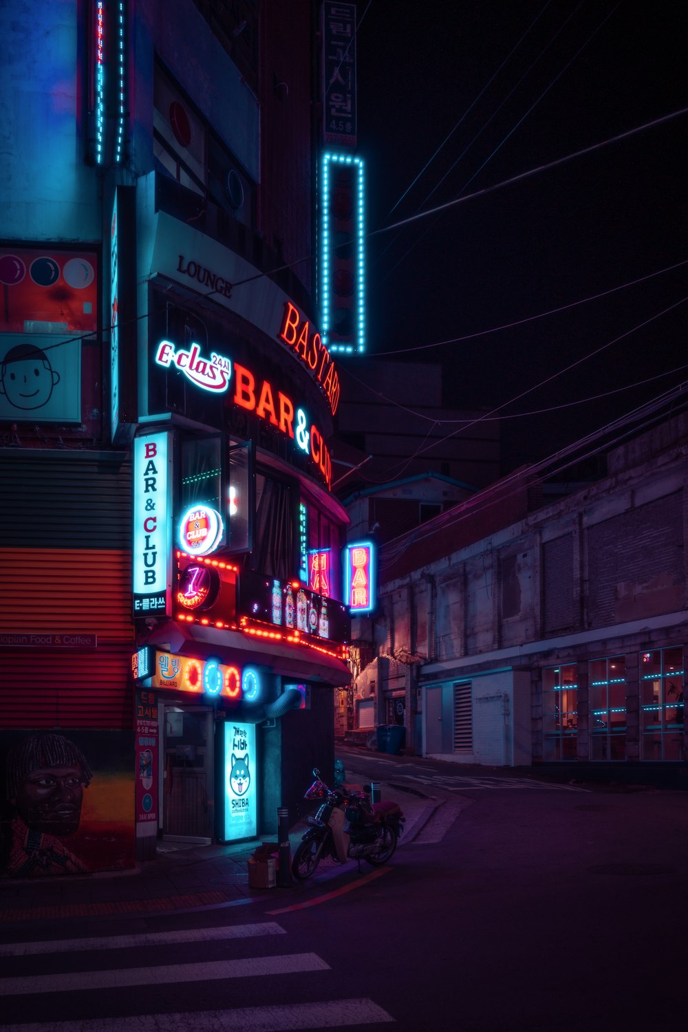 a dark street with neon signs and a motorcycle parked in front of it