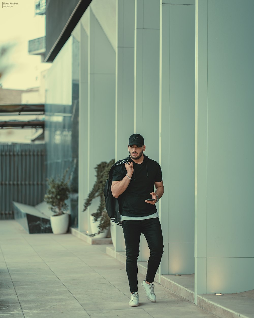 a man walking down a sidewalk talking on a cell phone