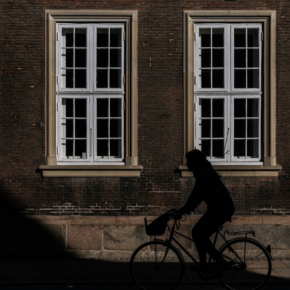 a man riding a bike past a tall brick building