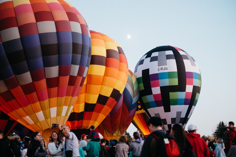 a group of people standing around a bunch of hot air balloons
