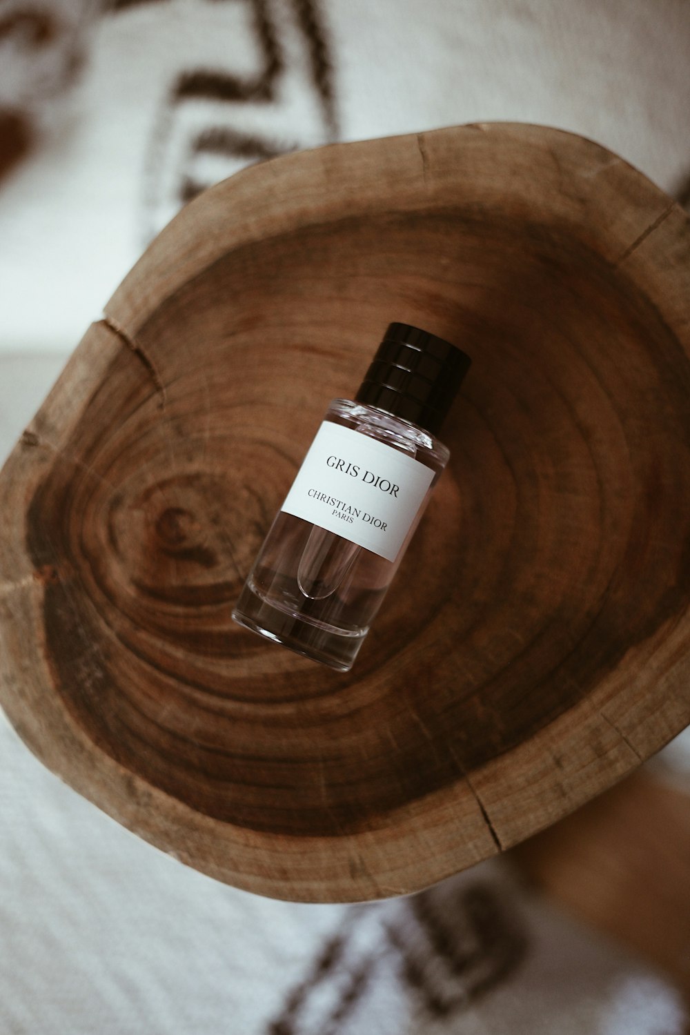 a bottle of cologne sitting on top of a wooden bowl